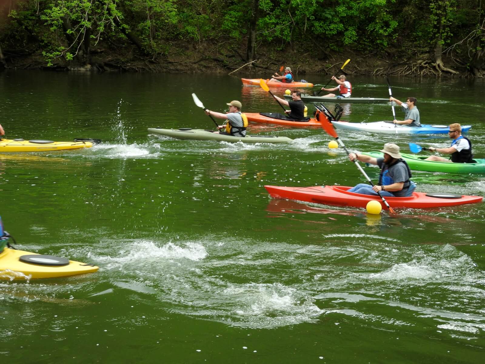 7 Best Family Vacations for Outdoor Fun - 6 A group of people enjoys outdoor fun, kayaking on a green river in colorful kayaks amidst lush trees, making the perfect scene for family vacations.