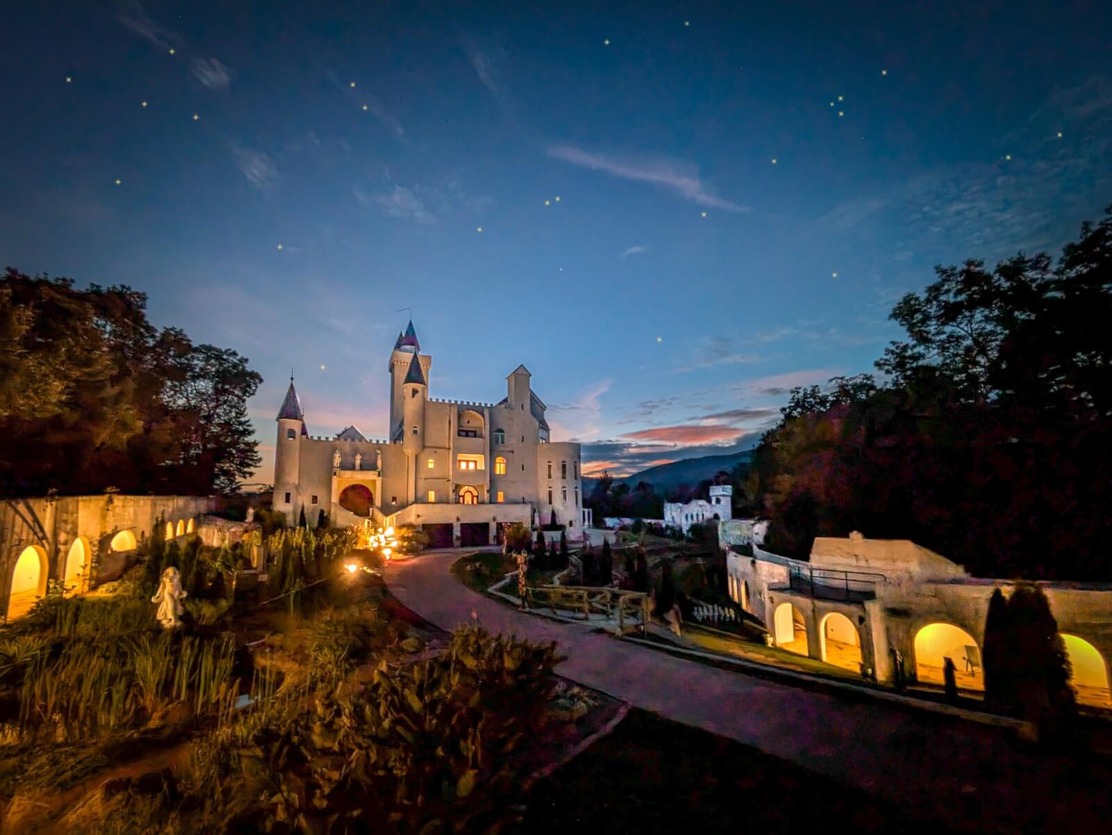 6 Southern Outdoor Getaways for the Adventure Traveler - 5 A large, illuminated castle surrounded by vibrant greenery and elegant arches at dusk, with a starry sky overhead invites the adventure traveler to explore Southern outdoor getaways filled with mystery and charm.