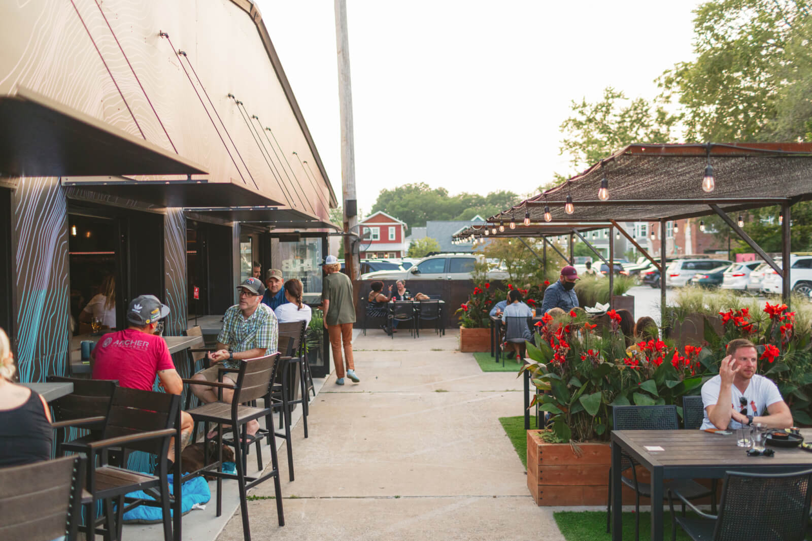 6 Southern Outdoor Getaways for the Adventure Traveler - 18 The outdoor patio of this Southern Outdoor Getaway exudes charm, with diners seated at tables surrounded by large red flowers and string lights twinkling above. It's a picturesque haven for any adventure traveler seeking a delightful retreat.