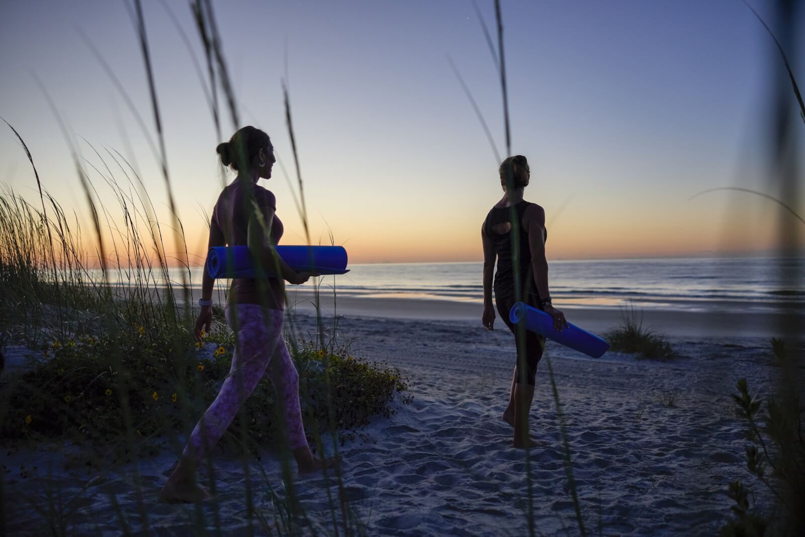 Georgia's 6 Best Girlfriends' Weekend Getaways - 12 Two women with yoga mats, walking on the sand toward the beach.