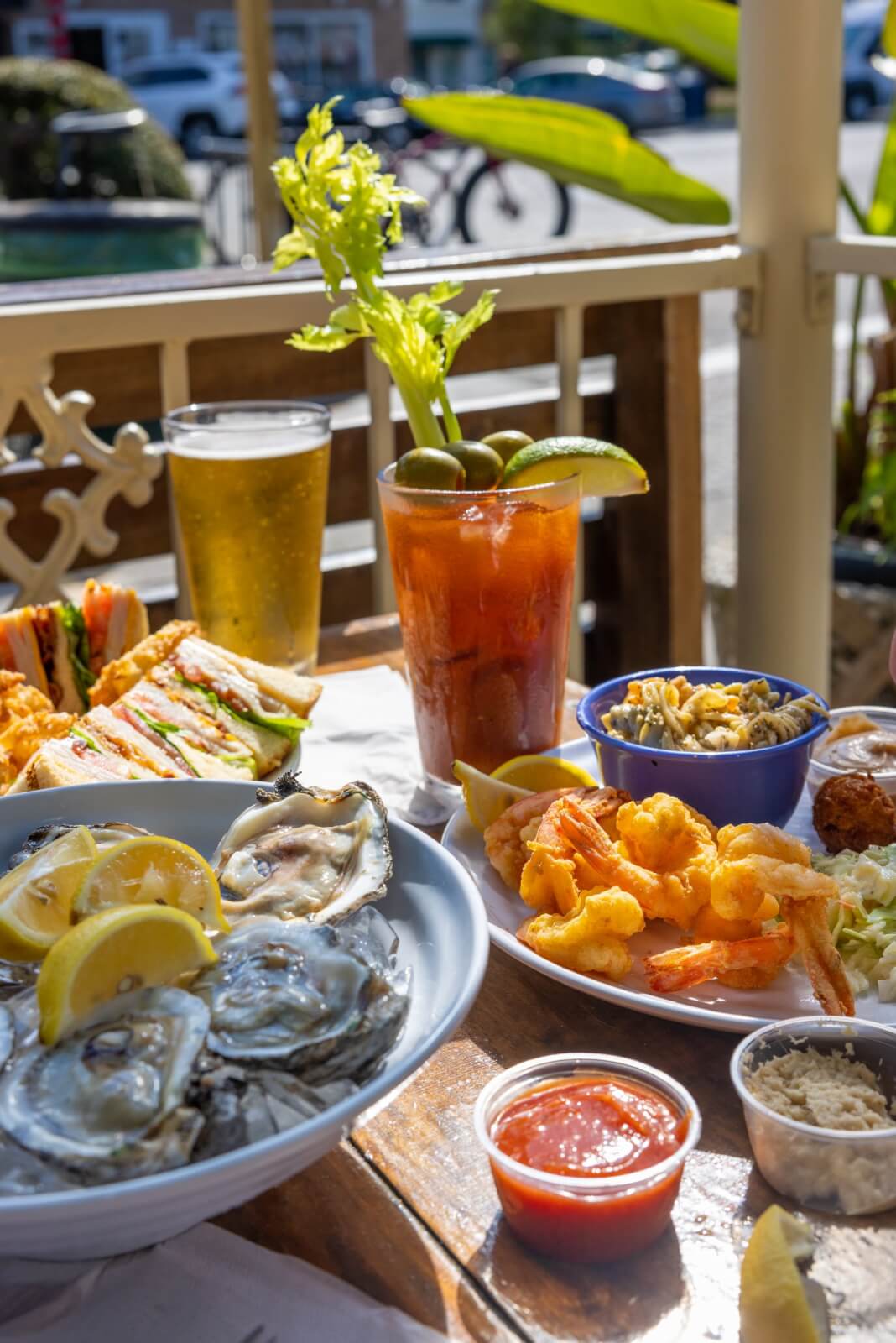 Georgia's 6 Best Girlfriends' Weekend Getaways - 10 Plates f food, including raw oysters and fried shrimp next to a Bloody Mary on a pati table.