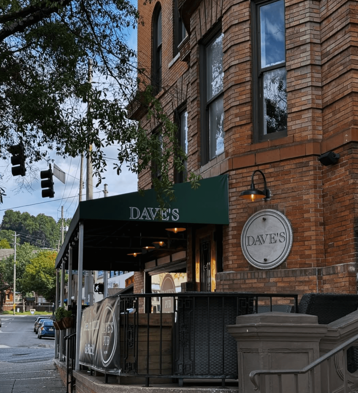 Brick building corner with a green awning labeled "DAVE'S" in Birmingham. A round sign with the same name hangs on the wall. Traffic lights and trees are visible in the background. Try this new restaurant this month for a memorable dining experience!.