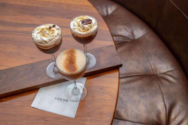 A martini flight featuring three espresso martinis sits elegantly on a wooden table beside a crisp napkin at Mason Bar.