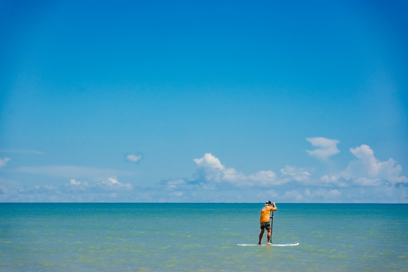 A man on a paddleboard floats on the blue ocean waters.
