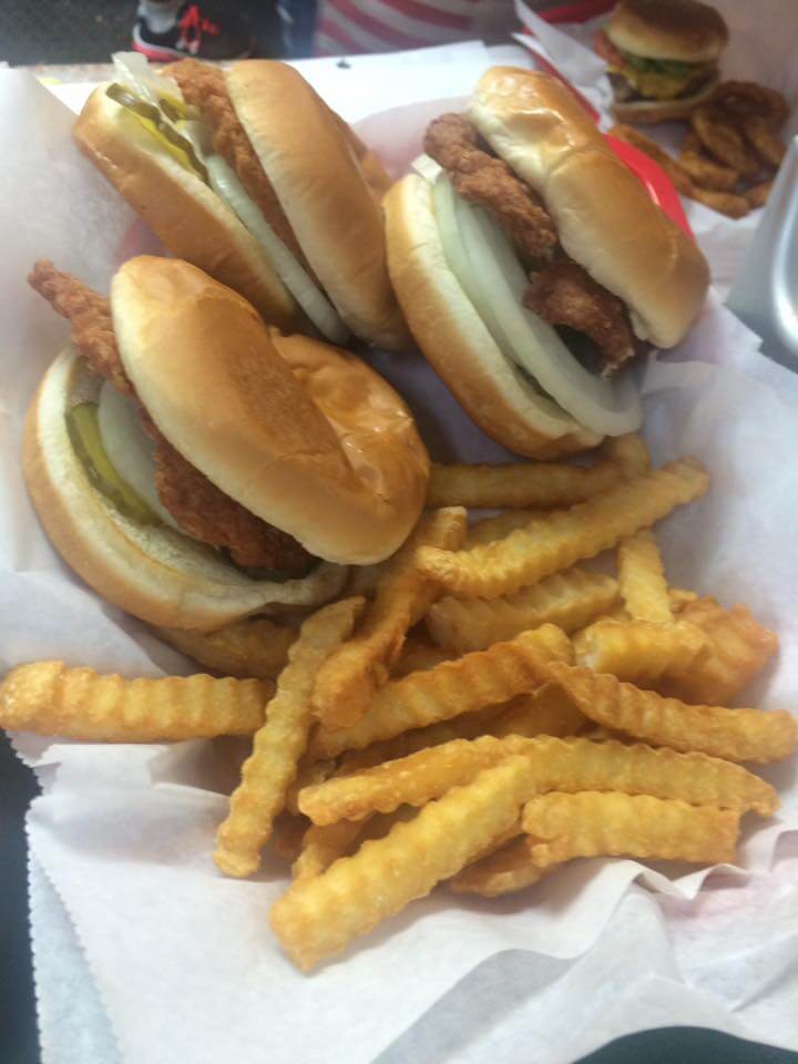 Two slugburgers with onion and pickle, paired with crinkle-cut fries in a paper-lined basket.