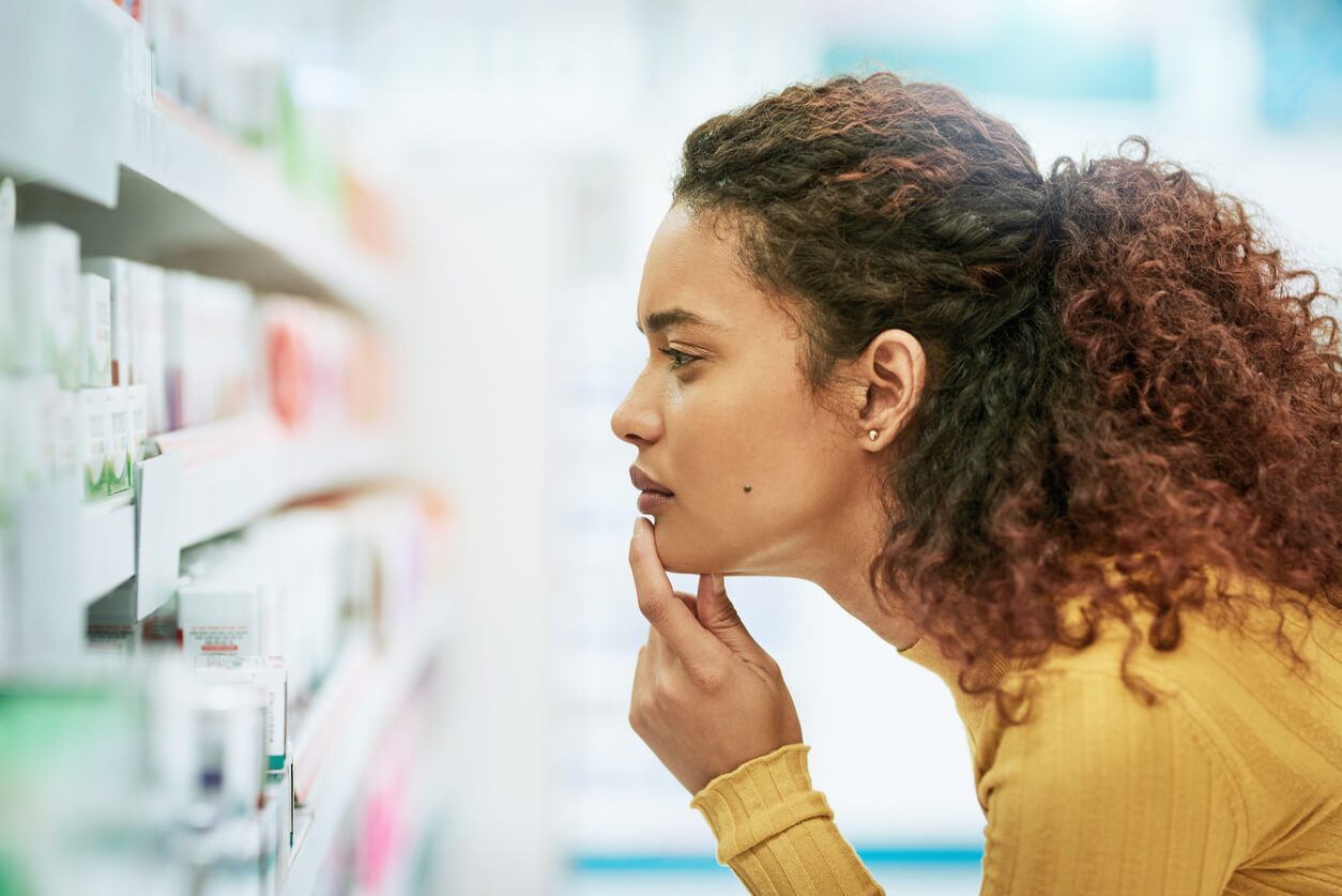 Is This Medical Bias Harming Your Health? - 1 Person in a yellow sweater examines products on a store shelf, expressing a thoughtful demeanor, perhaps considering the impact of gender bias in healthcare on their choices.