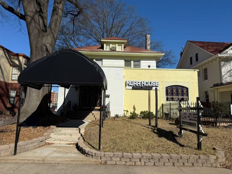 Two-story building with a large tree beside it exudes Southern charm. The sign reads "Kora House." A dark canopy covers the entrance with steps that seem to invite you into one of Memphis' hidden gem restaurants.
