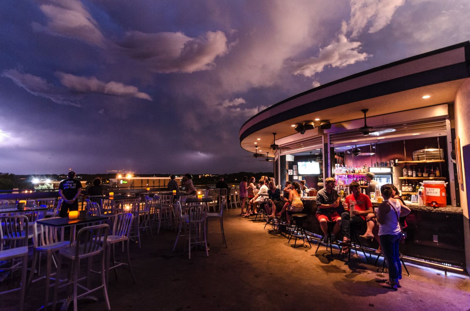 Georgia's 6 Best Girlfriends' Weekend Getaways - 6 People sit at tables and a bar on an outdoor patio at dusk, under dramatic clouds and a purple sky.