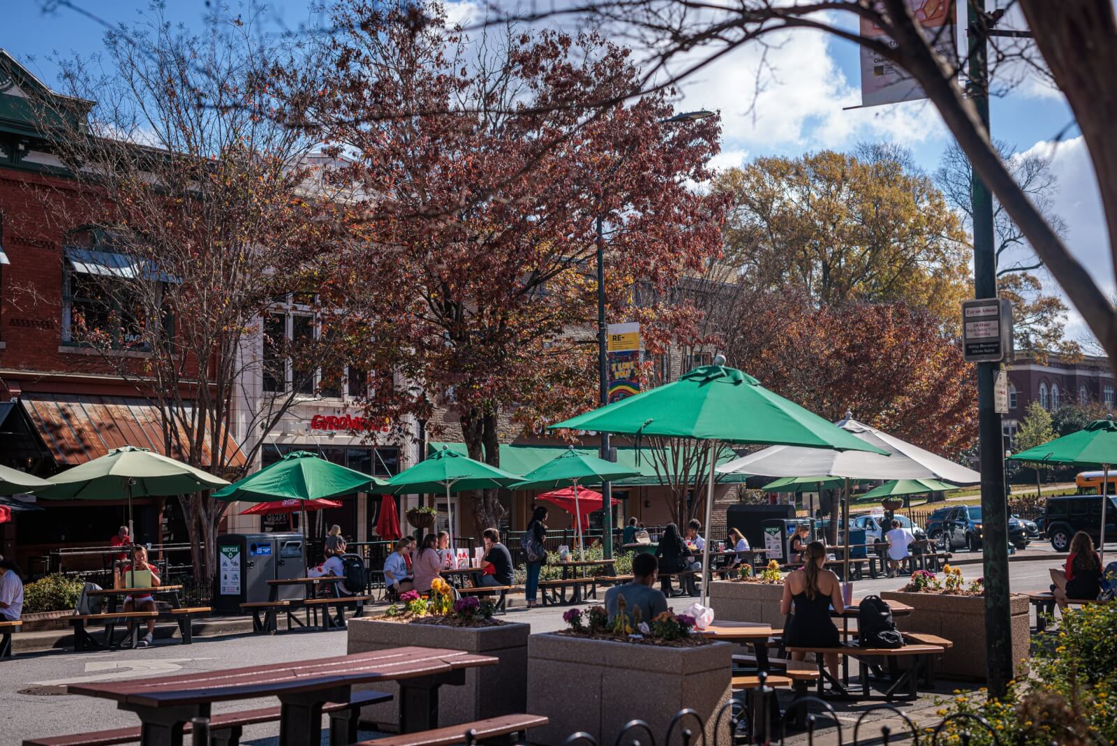 Georgia's 6 Best Girlfriends' Weekend Getaways - 4 People enjoy outdoor tables with green umbrellas along a sunny city street with trees and buildings providing a charming backdrop.