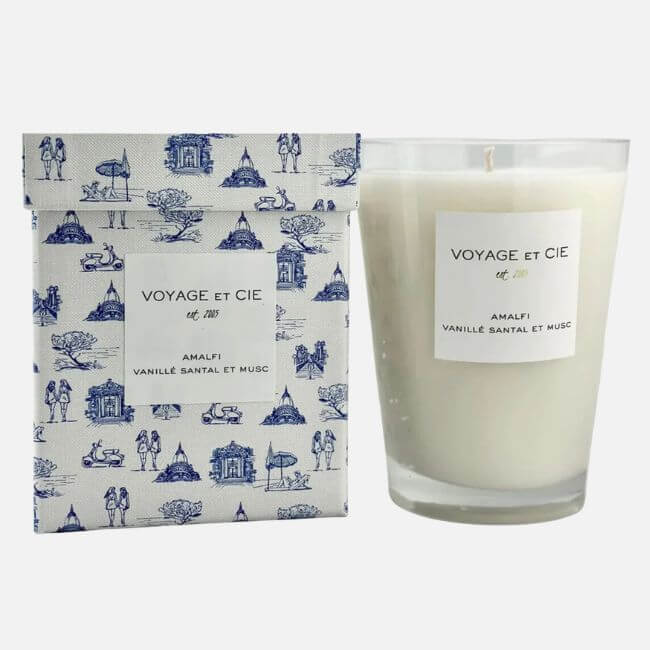 19 Fresh FINDS Around BHAM: Closet Refreshers, Entertaining Picks & More - 14 A white candle in a clear glass holder labeled "Voyage et Cie Amalfi Vanille Santal et Musc" sits beside a blue toile print box with a matching label—an elegant Birmingham FINDS April favorite.