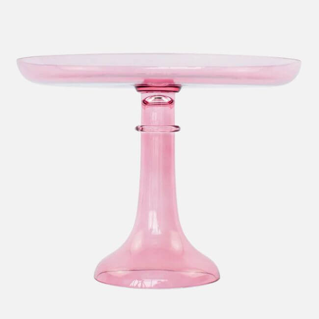 19 Fresh FINDS Around BHAM: Closet Refreshers, Entertaining Picks & More - 12 A translucent pink glass cake stand with a wide, round top and sturdy pedestal base, featured as one of Birmingham FINDS April highlights, shown on a plain white background.