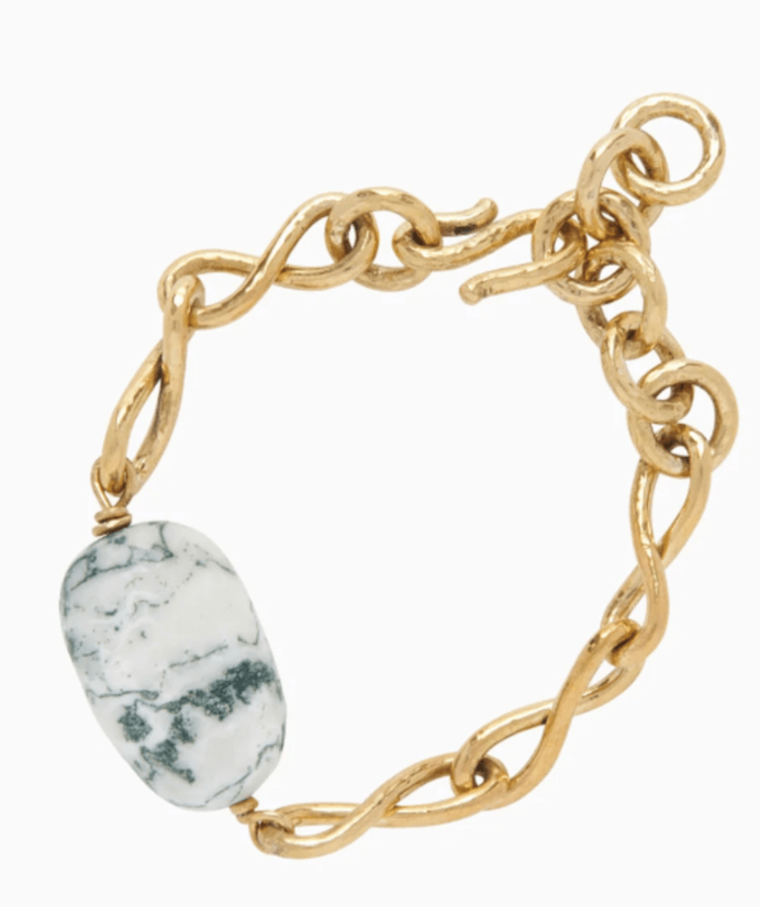 A gold chain bracelet with a large, oval white stone featuring dark green veining, connected by a toggle clasp.