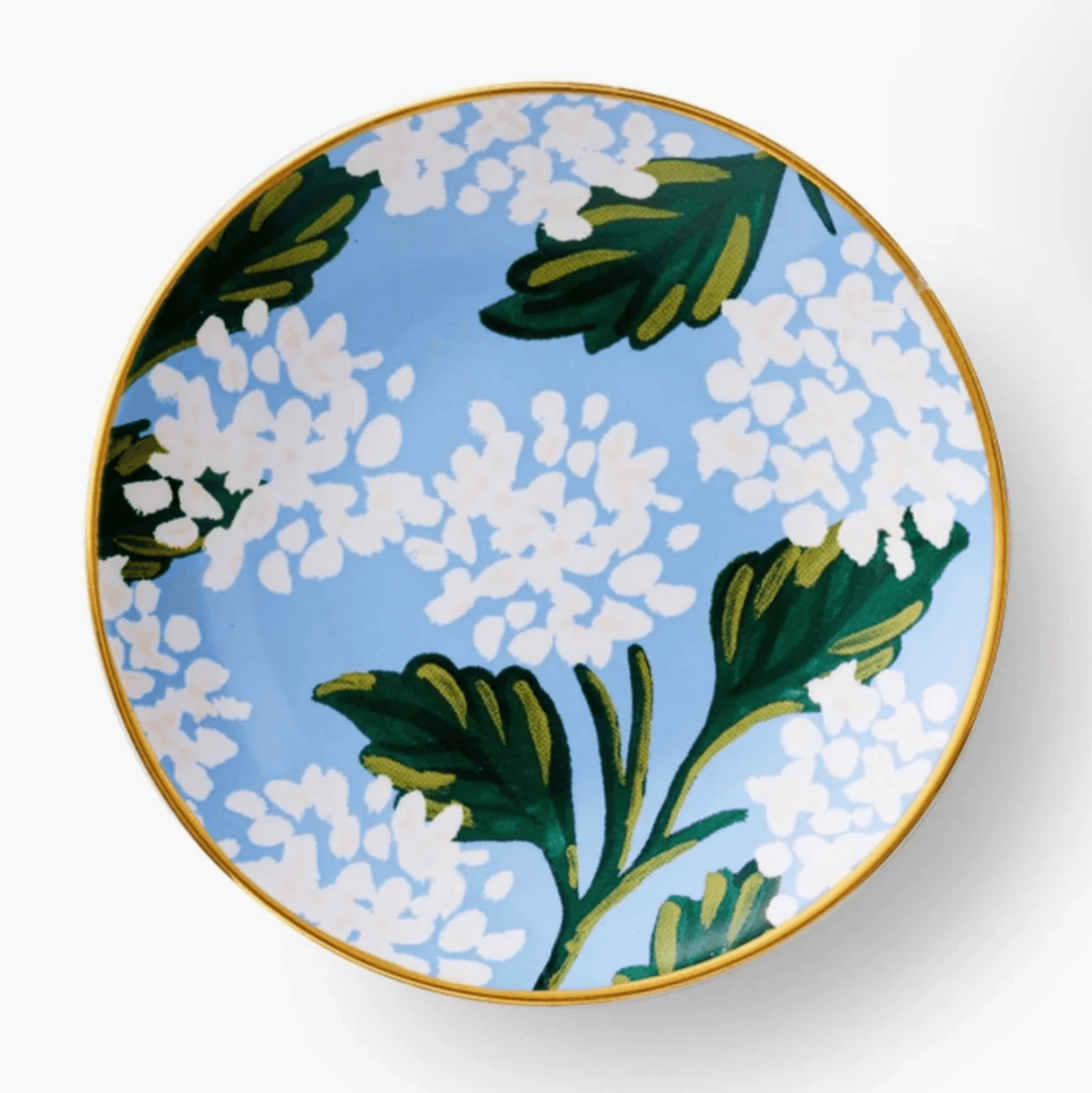 A round ceramic plate with a gold rim, featuring a blue background and a floral pattern of white flowers and green leaves.