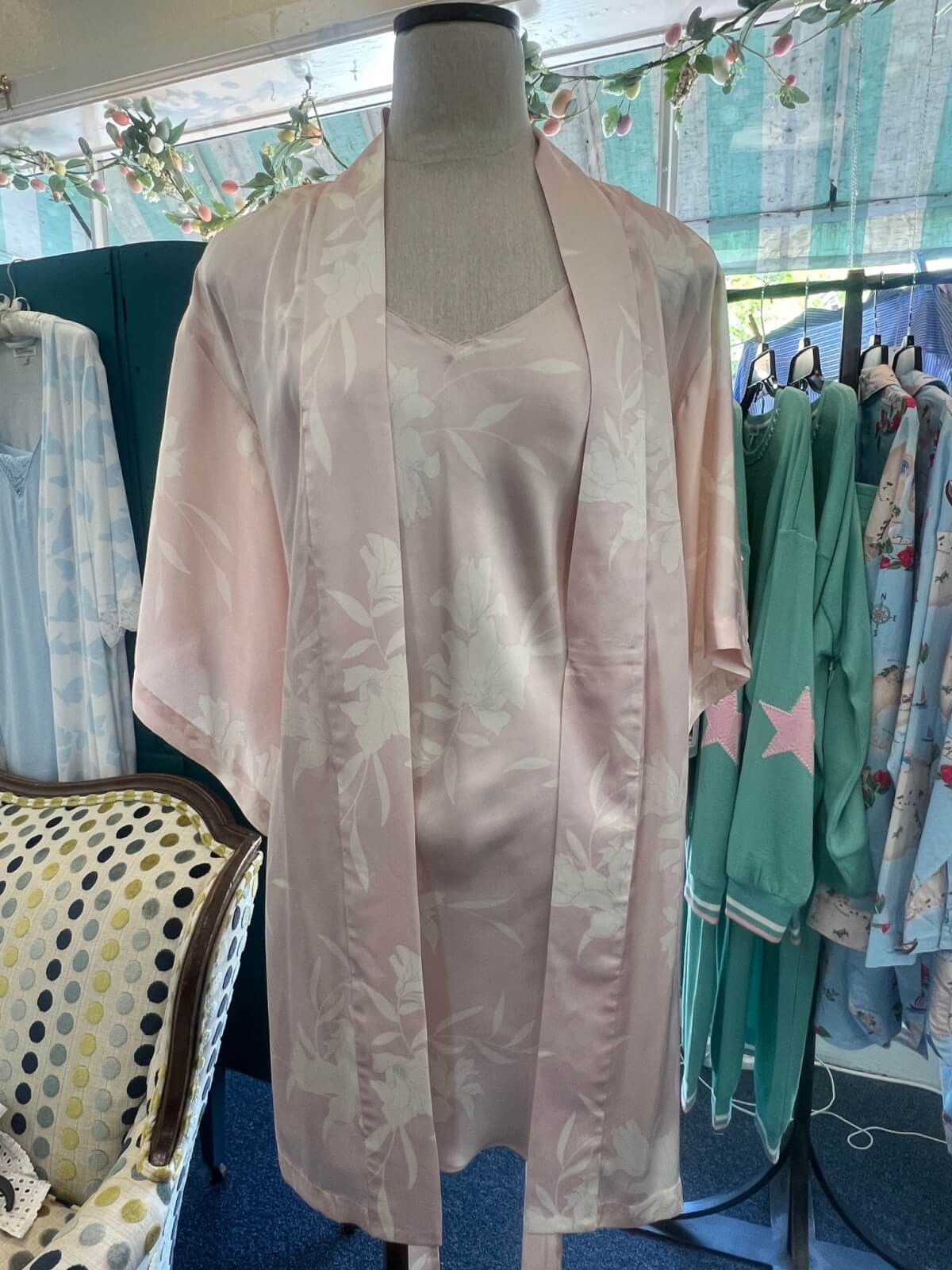 A mannequin displays a pale pink satin floral robe and matching slip dress.