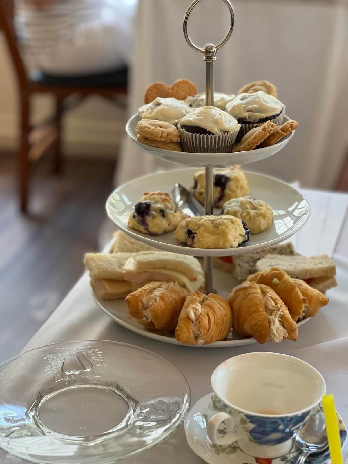 A three-tiered tray with pastries, scones, sandwiches, and desserts sits on a table with a teacup—perfect for a Mother’s Day brunch in Birmingham, AL.