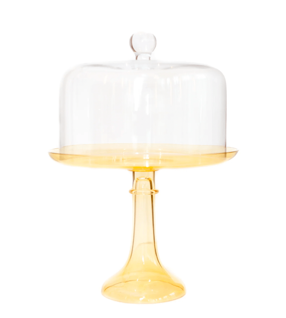 12 Colored Glass Accessories We Love: Cake Stands, Candlesticks & More - 2 A yellow colored glass cake stand with a tall base and a clear glass dome cover on top.