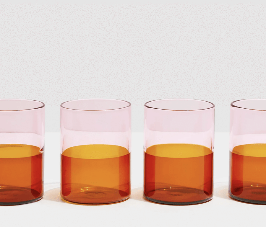 12 Colored Glass Accessories We Love: Cake Stands, Candlesticks & More - 6 Four elegant glass items, half-filled with amber liquid, are arranged in a line against a plain background.
