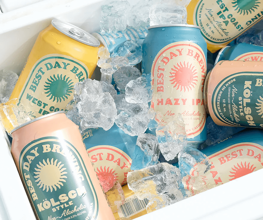 A variety of colorful canned beverages labeled "Best Day Brewing" are chilled on ice in a cooler, ready to refresh. 