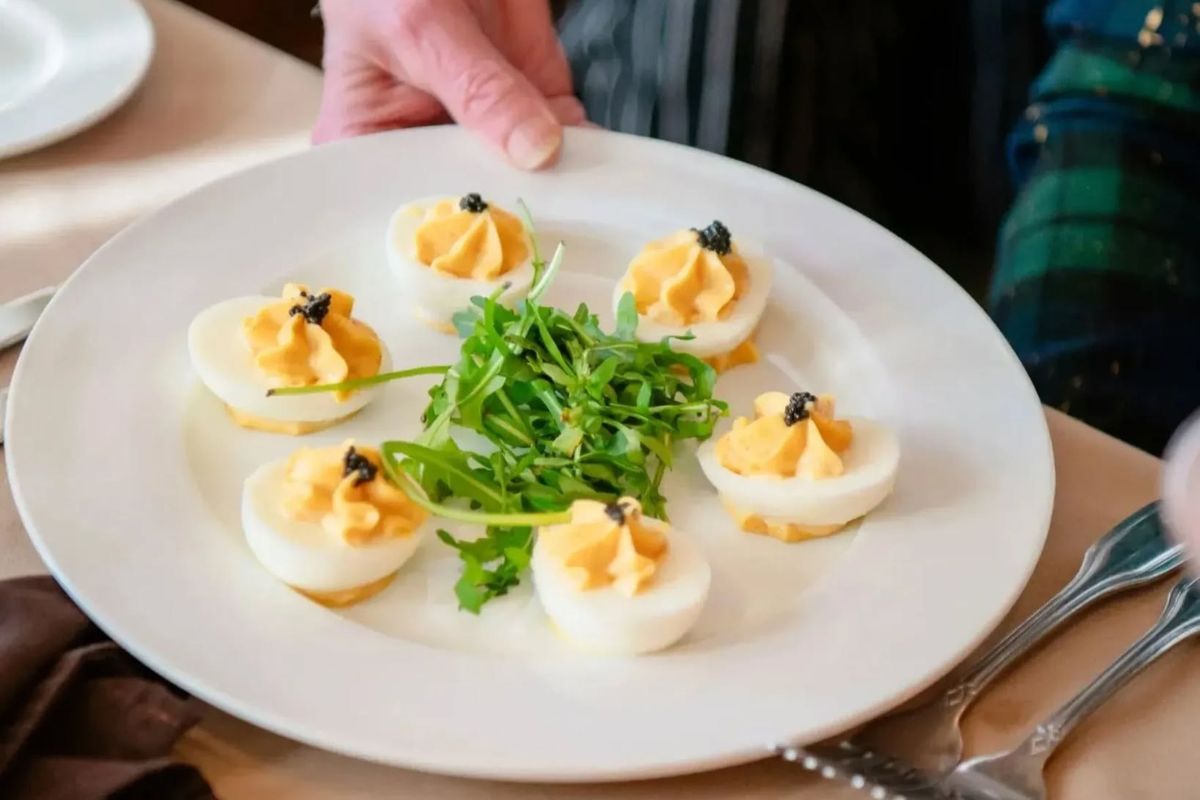 A plate of six deviled eggs garnished with herbs and caviar, served around a small pile of arugula greens—perfect for an elegant brunch in Memphis.