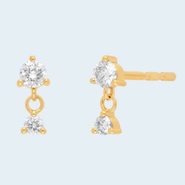 15 Memphis FINDS at Local Shops: Spring Dresses, Home Decor & More! - 12 A pair of gold stud earrings each featuring two round white gemstones, one fixed and one dangling below, showcased as part of Memphis FINDS April on a light background.