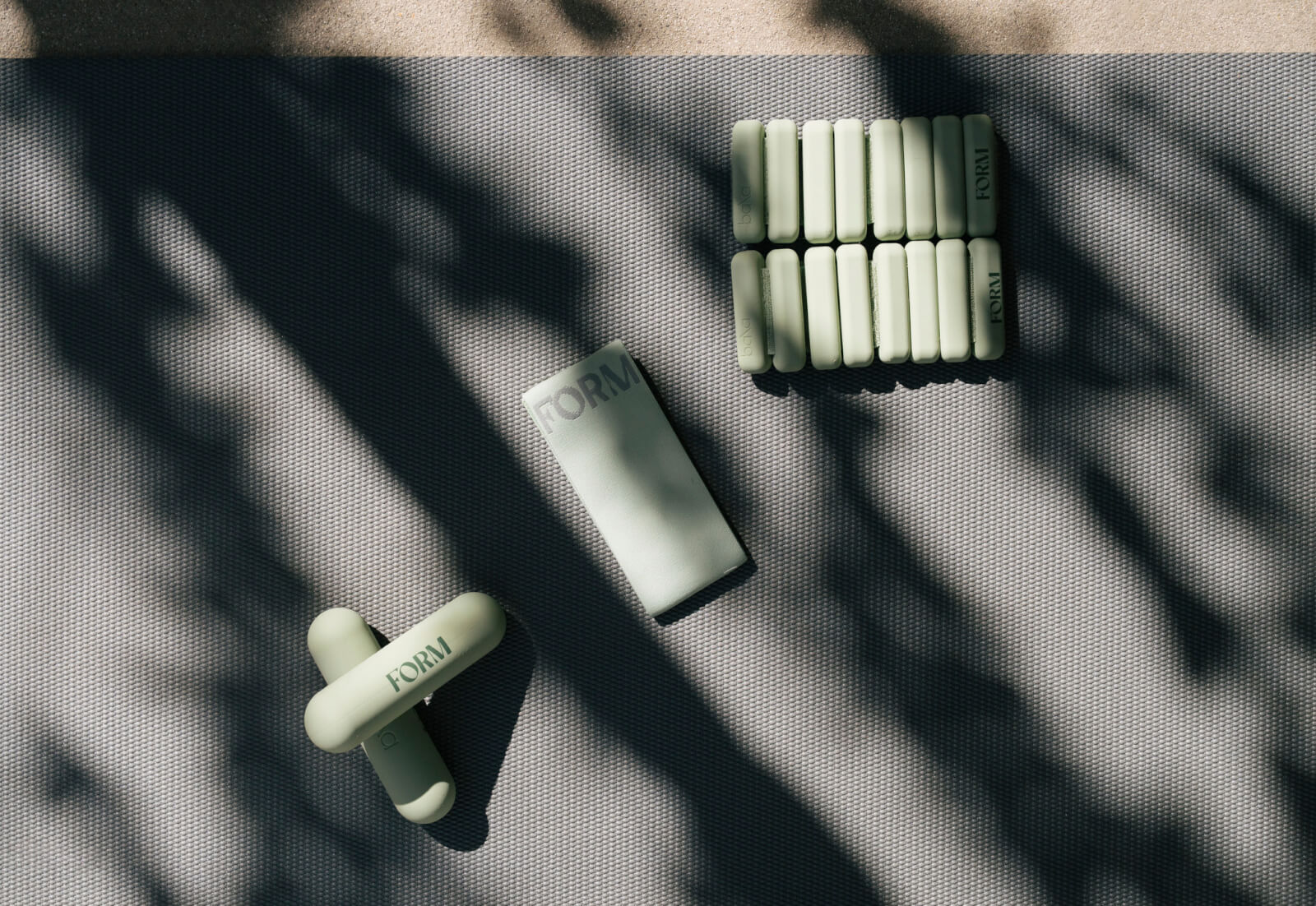 5 Nashville Hotels with Outstanding Wellness Programs - 1 Set of light green exercise weights labeled "FORM" arranged on a gray textured mat, with dappled sunlight and shadow patterns.