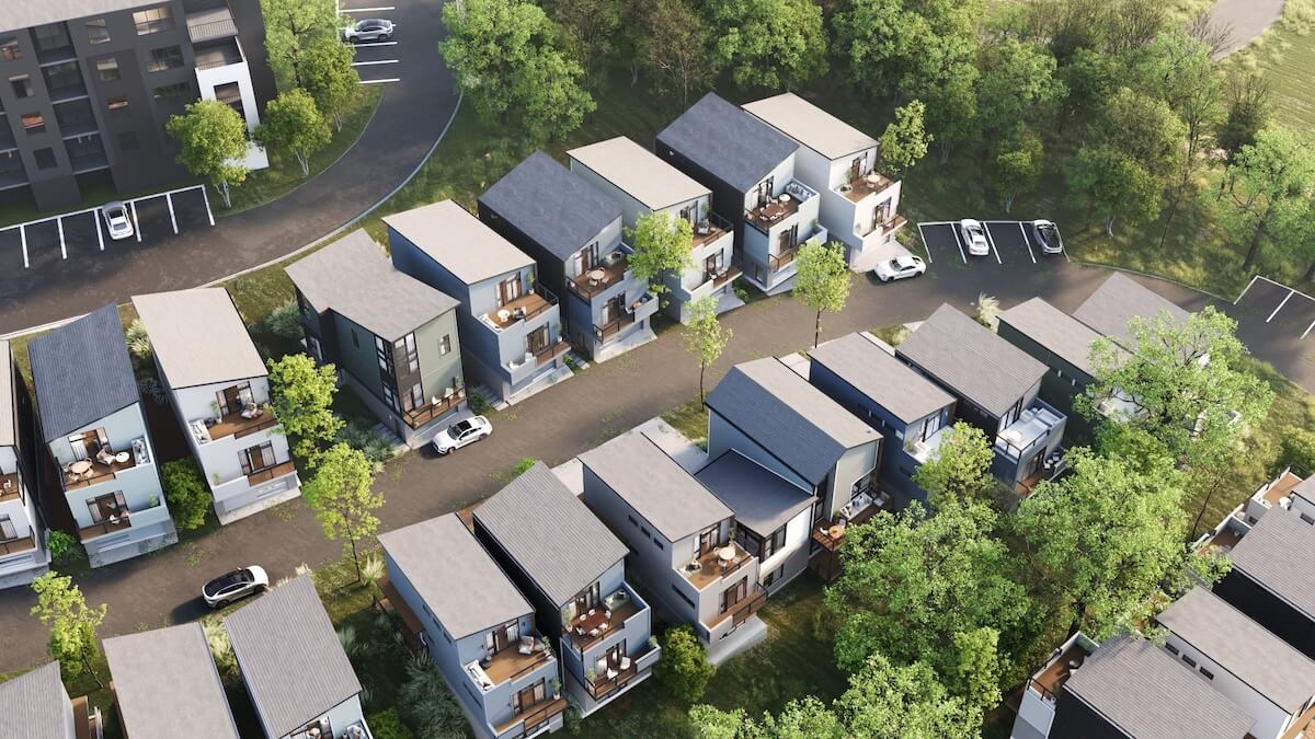 Aerial view of new developments in East Nashville, featuring rows of modern two-story homes, tree-lined streets, parked cars, and nearby open parking spaces.