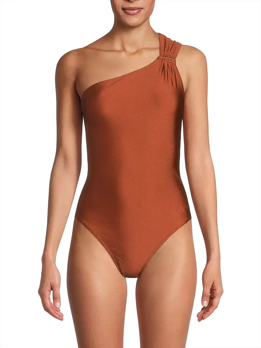A stylish woman wears a rust-colored, one-shoulder swimsuit with pleated detailing on the strap, standing against a plain background—perfect for summer.
