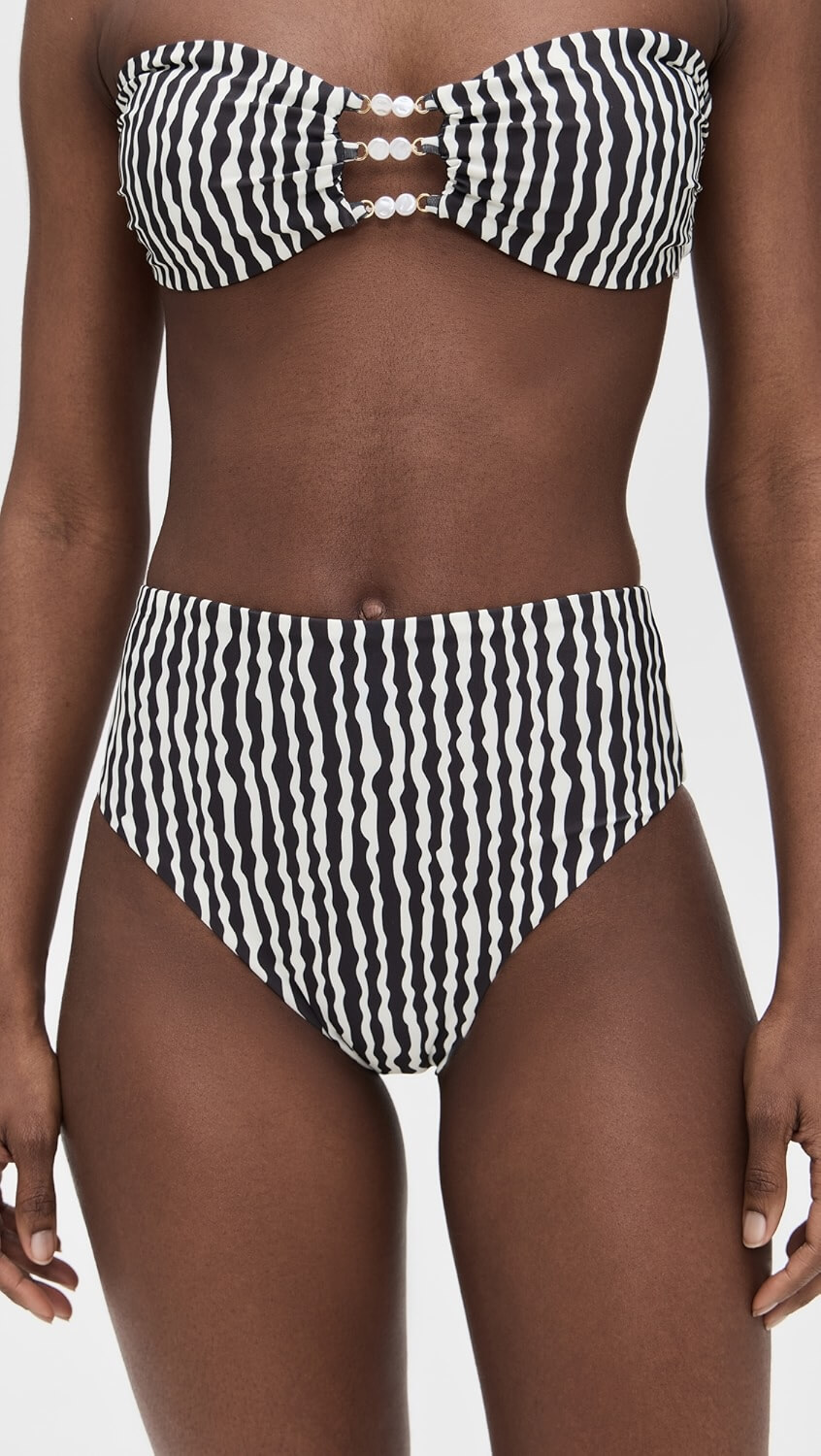 A stylish person wearing a black and white striped two-piece swimsuit with a strapless top and high-waisted bottom—perfect for summer days by the pool.
