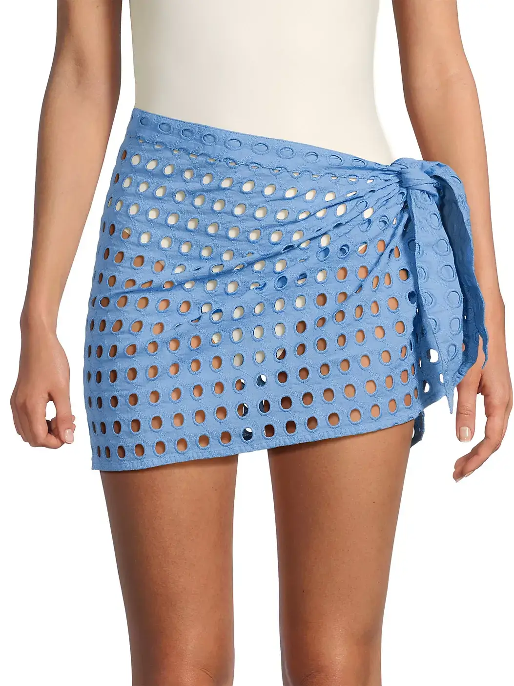 Stylish and perfect for summer, this look features a person in a white swimsuit paired with a light blue perforated mini skirt, complete with a large side knot detail.