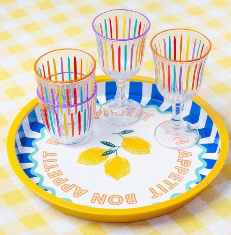 A round tray with a lemon design, the words "Bon Appétit," and four clear glasses with colorful vertical stripes on a yellow and white checkered tablecloth—perfect for Mother’s Day or unique Nashville grad gifts.