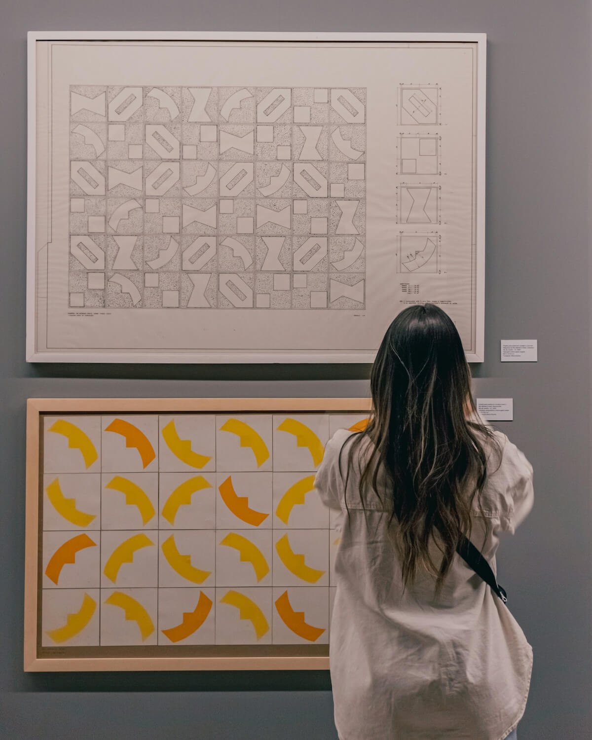 Aligning Your Money with Your Values: A Guide to Intentional Spending - 1 A person admires geometric art, featuring pencil sketches and diagrams, alongside a vibrant pattern of yellow and orange shapes on a grid.