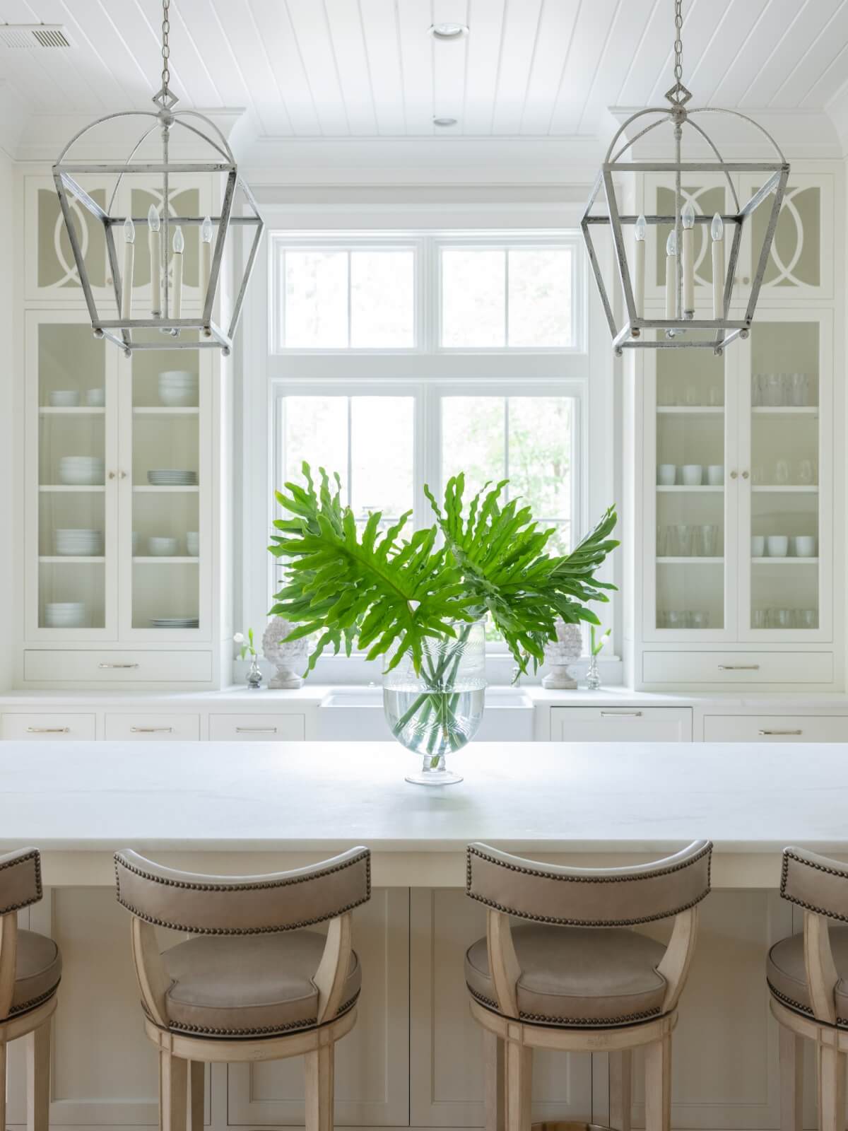 An earth-toned kitchen with greenery on the island.