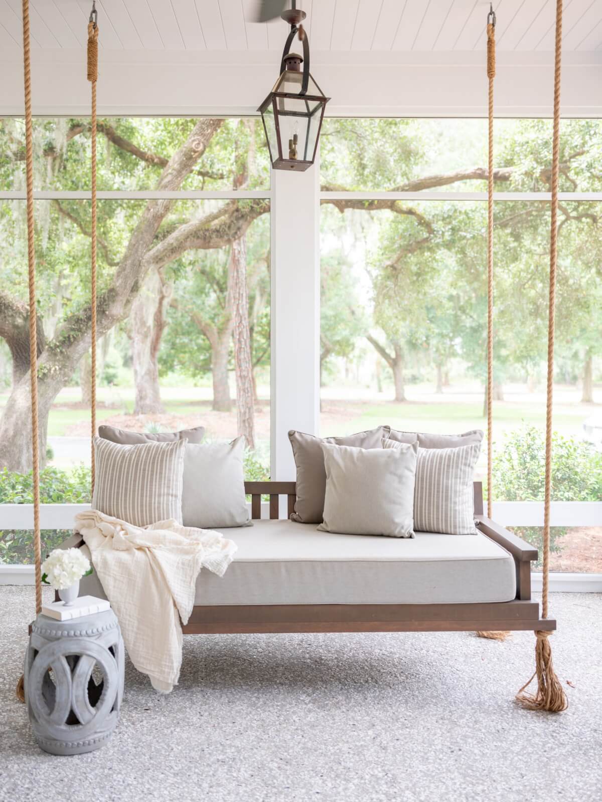 A front porch with a wooden swing and white throw pillows