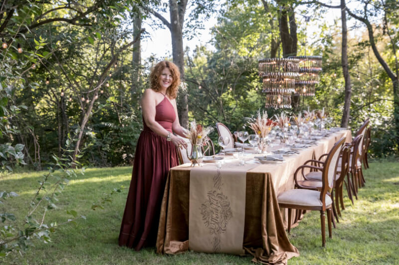 Angie in a burgundy dress, setting an outdoor table.