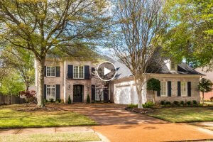 Nestled in the charming community of Almadale Farms, this two-story brick house at 1938 Almadale Farms Pkwy in Collierville, TN, features a large garage, black shutters, and a well-maintained lawn framed by tall trees along the driveway.