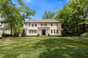 This two-story white house on Sheppard Place in Nashville, Tennessee features symmetrical windows, a centered front door, and is surrounded by trees and a large, neatly mowed lawn under a clear blue sky.