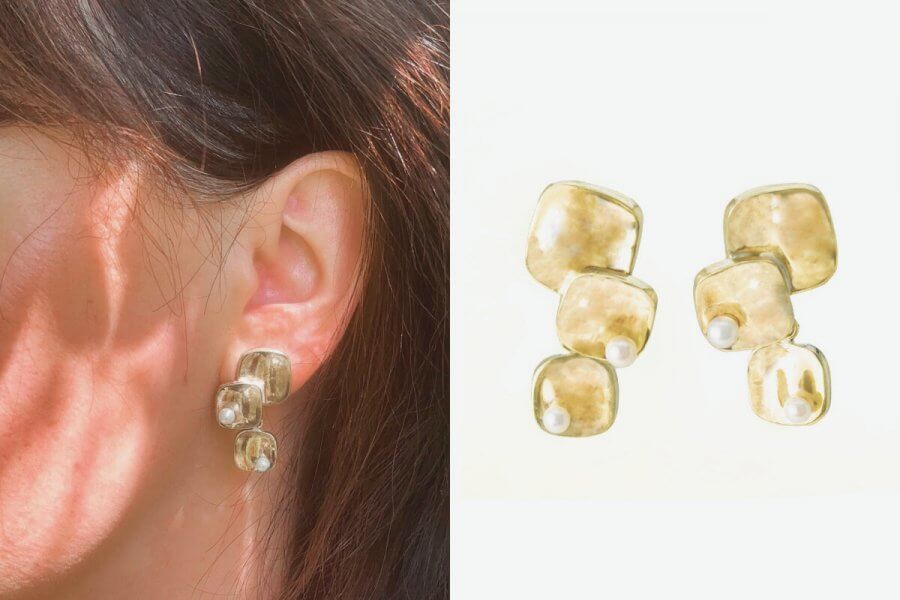 A close-up of a person’s ear wearing gold-toned, geometric earrings with pearl accents is shown next to a clear product image of the same earrings, available at select Nashville shops.