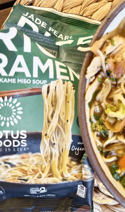 A package of Lotus Foods Jade Pearl Ramen with Wakame Miso Soup sits next to a bowl of prepared ramen, making for an easy noodle bowl with vegetables and broth.