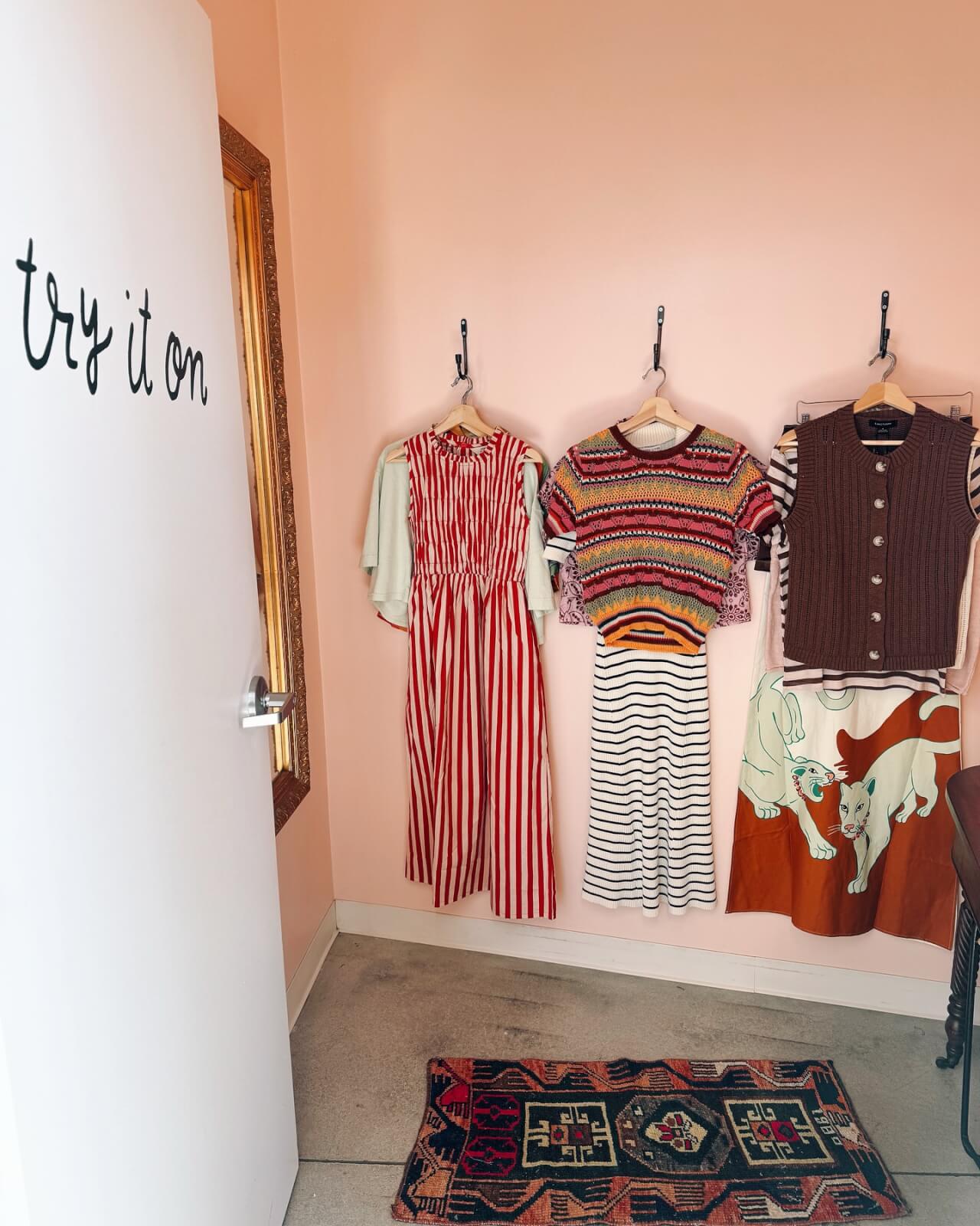 Georgia's 6 Best Girlfriends' Weekend Getaways - 13 A fitting room in Georgia with a white door labeled "try it on" and three dresses hanging on wall hooks, next to a patterned rug.