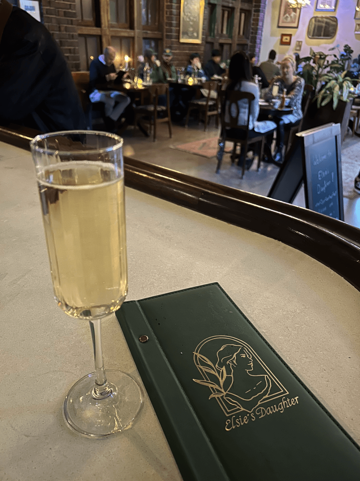 a glass of champagne next to an Elsie's Daughter menu on the bartop inside of a restaurant at Chattanooga Choo Choo. 