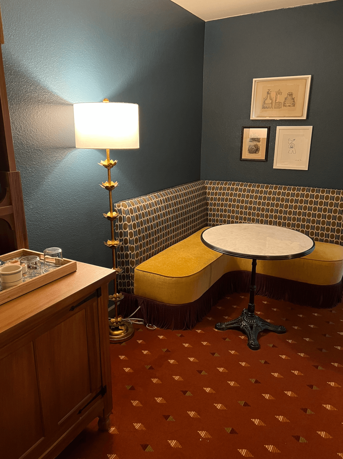 Inside the hotel chalet king suite with a booth and bistro table next to a lamp.
