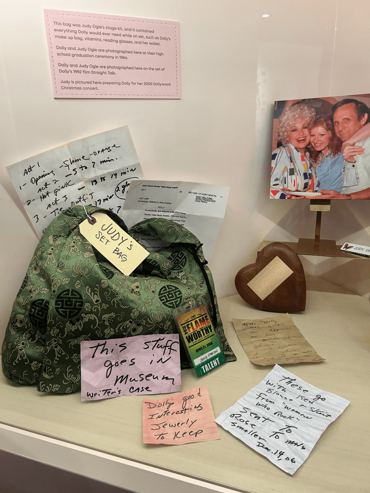 A highlight among Dollywood's things to do, this display case features Dolly Parton's green bag, handwritten notes, a green lighter, a photo of Dolly with two people, and a heart-shaped wooden box.