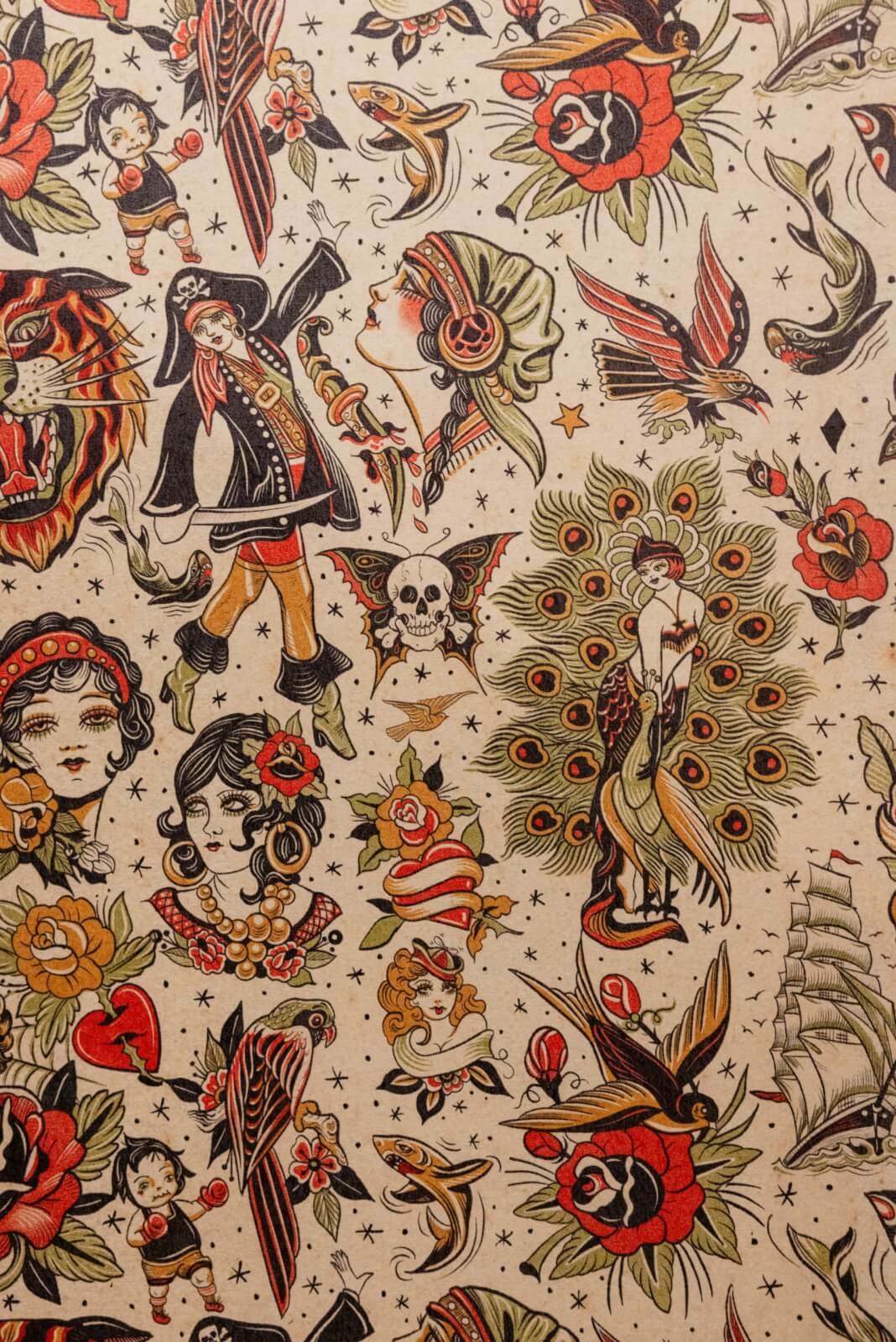 A patterned fabric featuring traditional tattoo-style illustrations—roses, swallows, a ship, a peacock, a skull, and vintage women—evoking the timeless charm of Memphis and the classic elegance of a vintage hotel.
