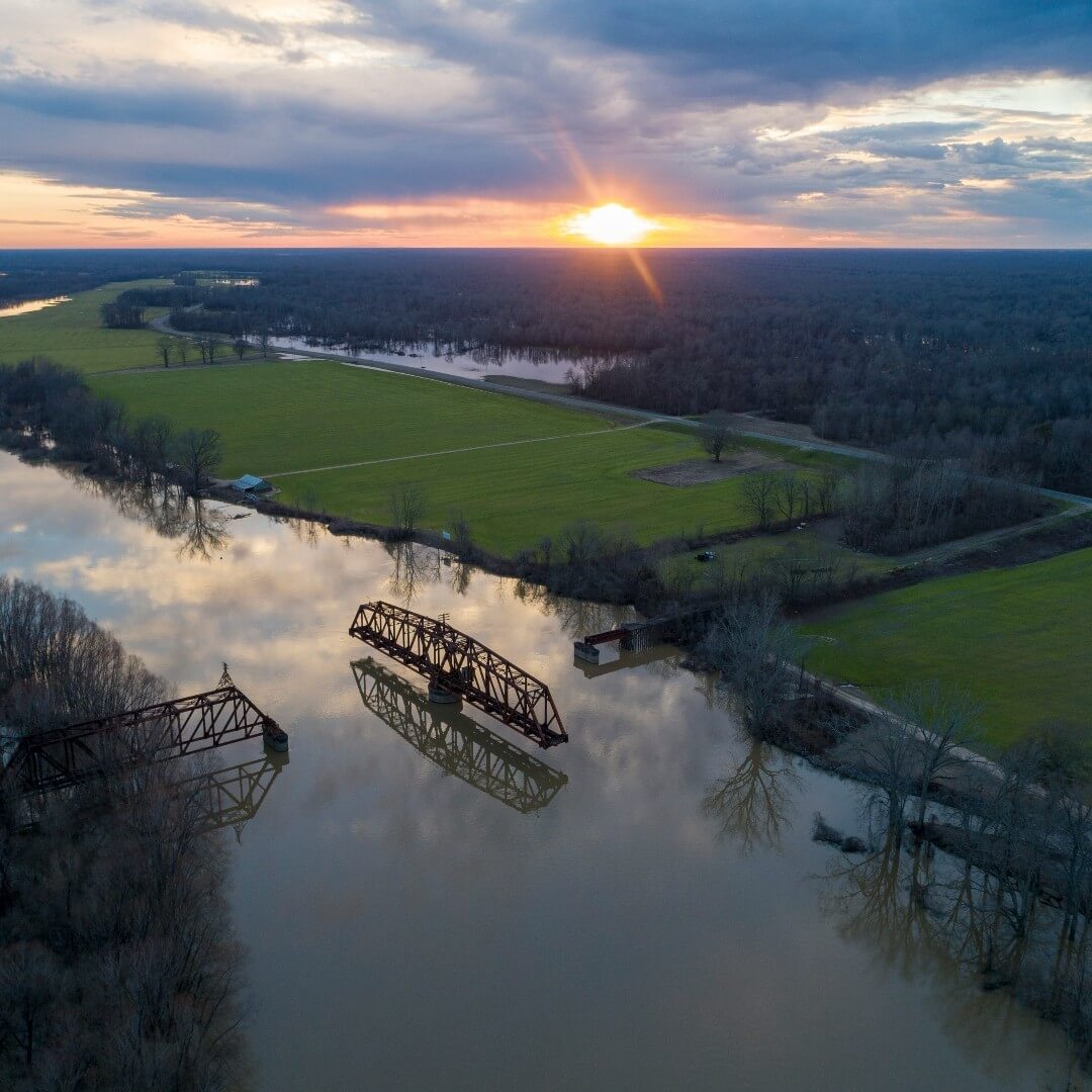 An aerial view of the Yazoo River with the middle piece of a bridge in the middle of the river standing perpendicular to its adjoining bridge pieces.