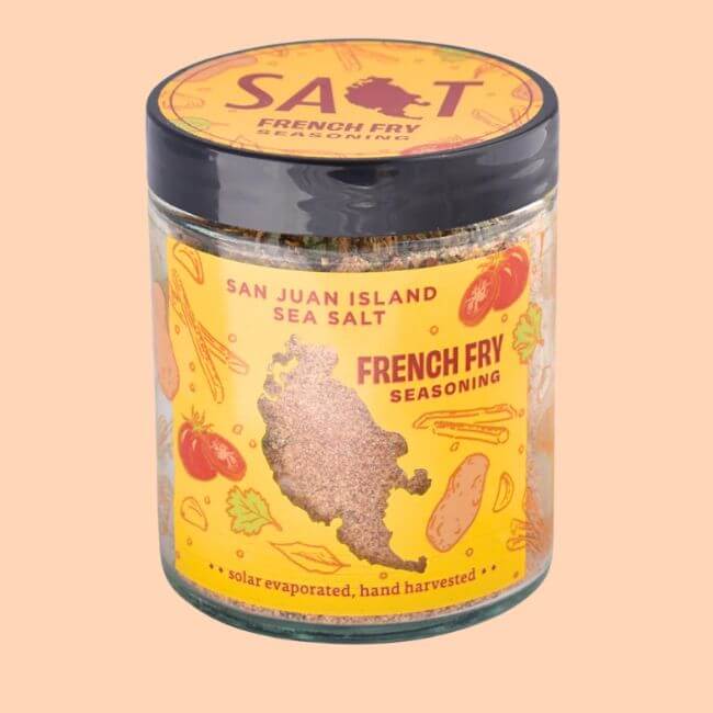 20 Spring FINDS for Mother’s Day & Beyond: Style, Beauty & Home Must-Haves - 21 A glass jar of San Juan Island Sea Salt French Fry Seasoning with a yellow label, illustrated vegetables, a map outline, and a black lid—perfect for adding flavor to your fries or gifting from Nashville shops.