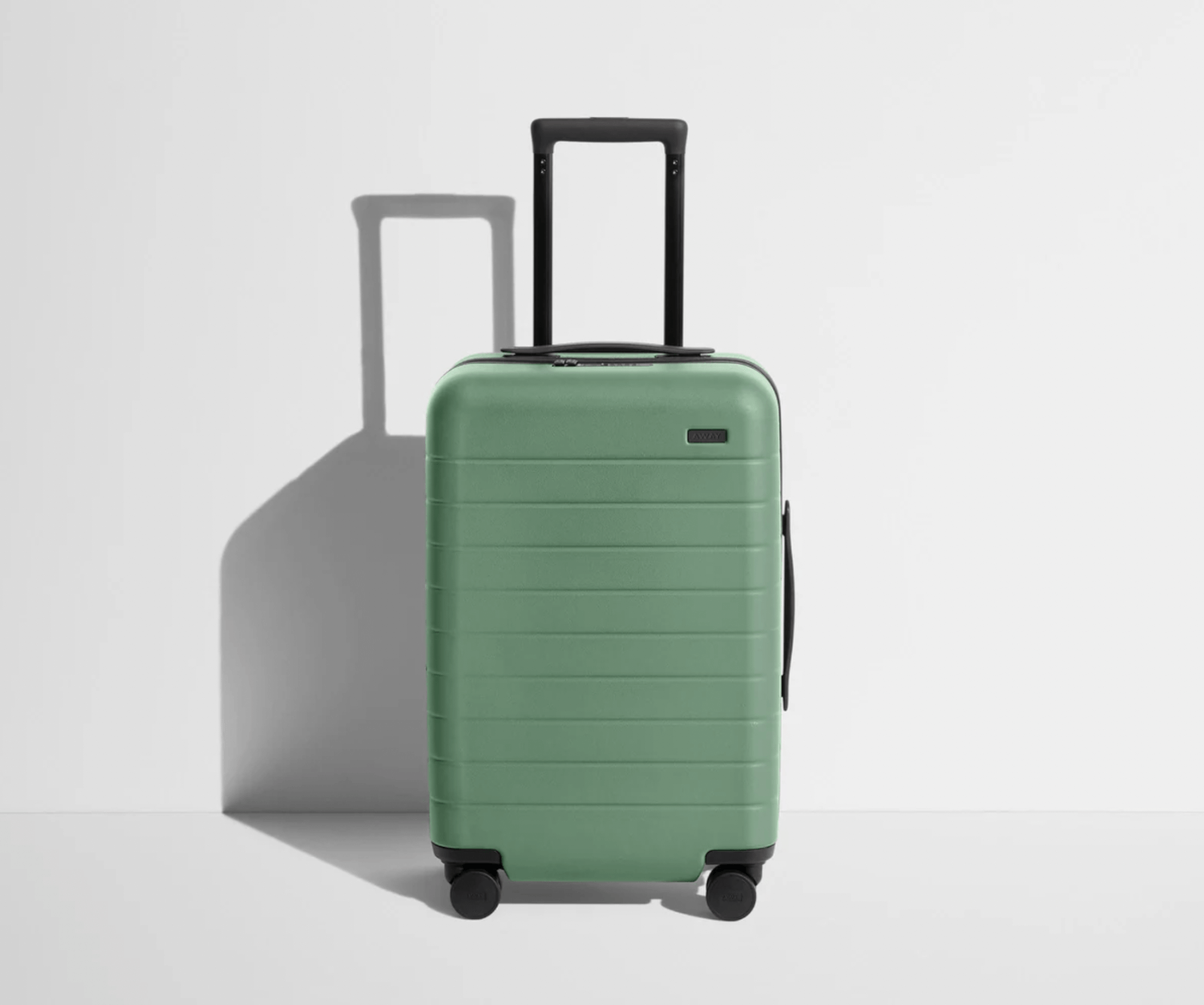 A mint green hard-shell travel luggage with four wheels, an extended black handle, and horizontal grooves is positioned against a plain white background.
