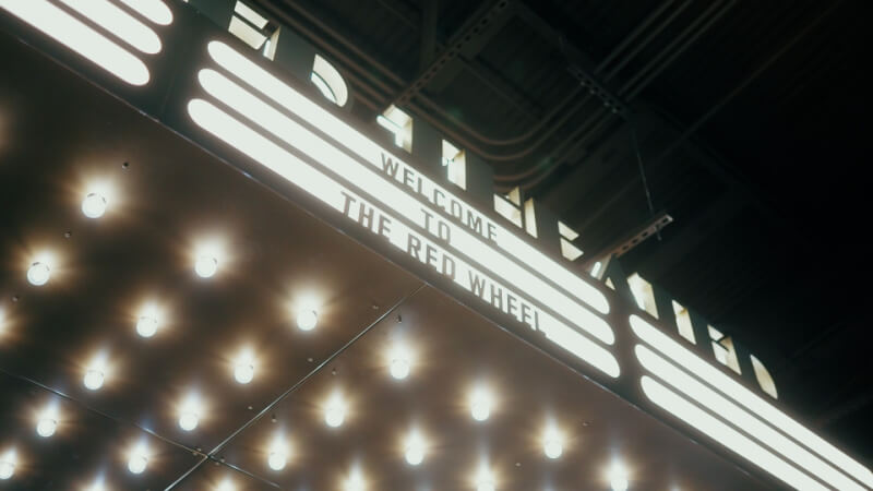 A marquee sign glows with "WELCOME TO THE RED WHEEL" in illuminated lights, casting a warm glow beneath the dark ceiling.