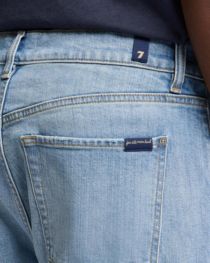 Close-up of the back pocket and waistband of light blue denim jeans, with a navy blue shirt partially visible and a "for all mankind" label—perfect summer vacation style or a standout pick for any Father’s Day Gift Guide.