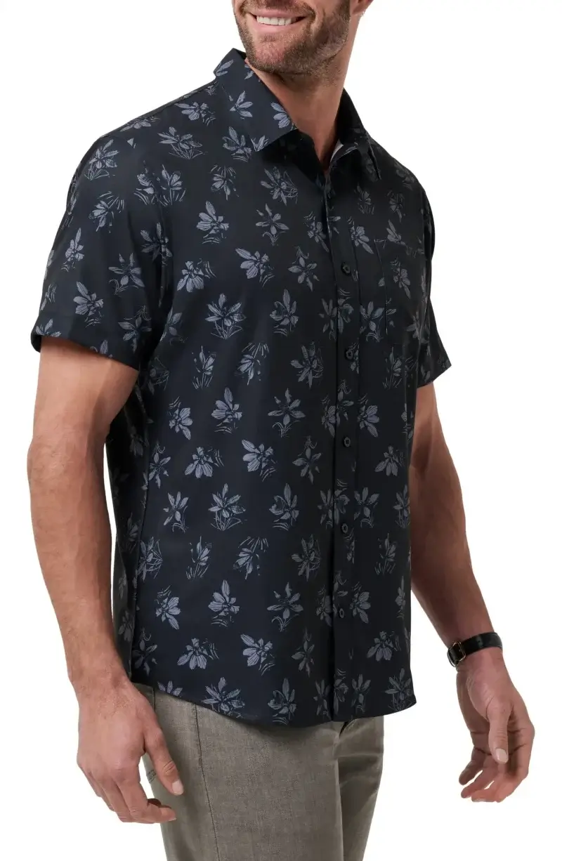 A man wearing a short-sleeve, black button-up shirt with a gray floral pattern and light-colored pants—perfect for a relaxed dad enjoying his summer vacation.