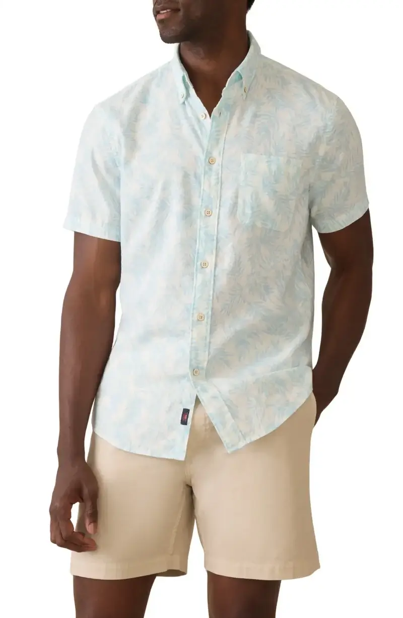 A man wearing a light blue patterned short-sleeve button-up shirt and beige shorts with his left hand in his pocket—perfect inspiration for your Father’s Day Gift Guide or stylish looks for a summer vacation.